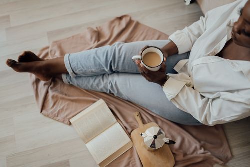 Free A woman enjoys a peaceful morning with coffee and a book indoors, capturing the essence of relaxation. Stock Photo