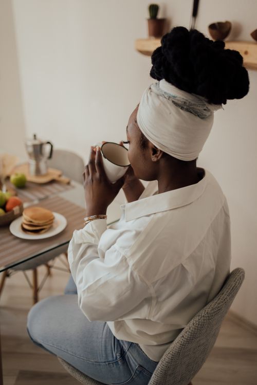 Free A woman enjoys a peaceful morning with coffee and pancakes at home, showcasing a relaxed lifestyle. Stock Photo