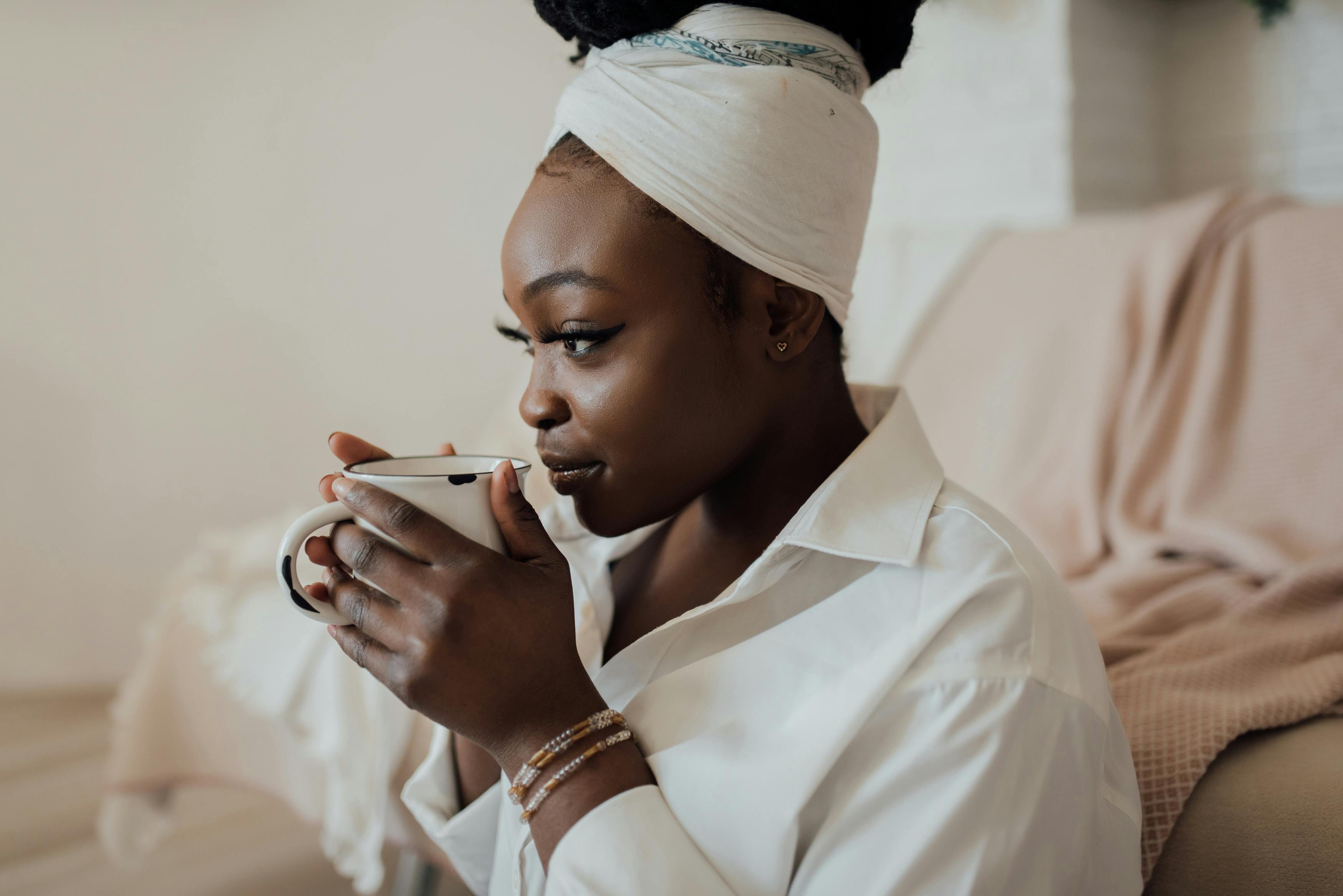 Woman in robe smiles while sipping from a mug.