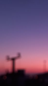 A blurred silhouette stands against a gradient sunset sky, creating an abstract, dreamy scene.