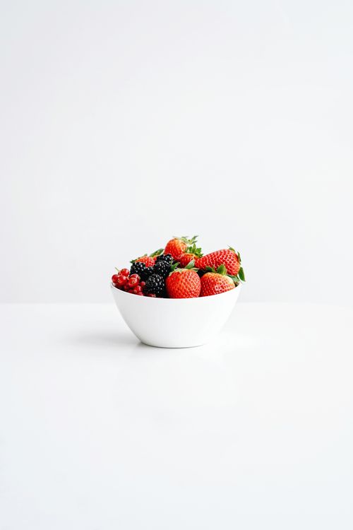 Free A bowl filled with fresh strawberries, raspberries, and blackberries on a white background. Stock Photo