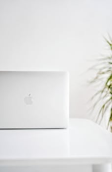 A sleek white laptop with an apple logo on a minimalist desk setting, ideal for modern workspace themes.