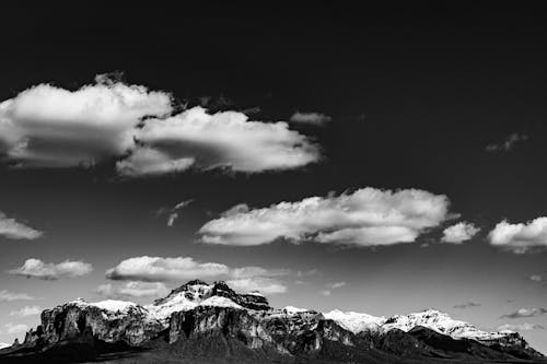 Grayscale Photo of Mountains under the Cloudy Sky