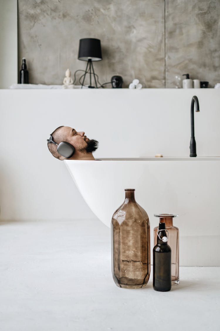 Man With Headphones Lying Inside A Bathtub