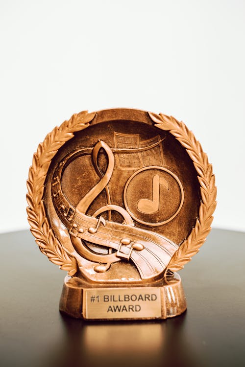Golden trophy with musical symbols and a treble clef, labeled '#1 Billboard Award' on a black table