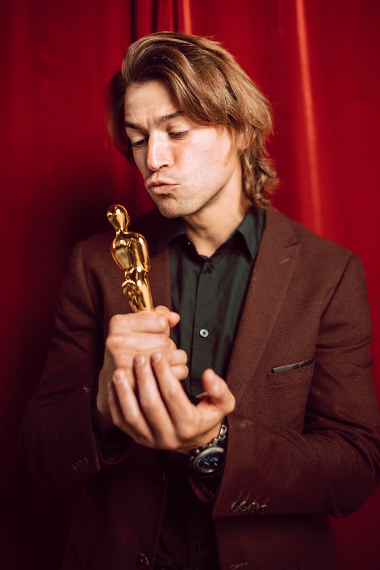 Man In Suit Jacket Holding Gold Trophy