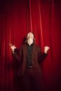 Woman in Black Coat Standing Near Red Curtain