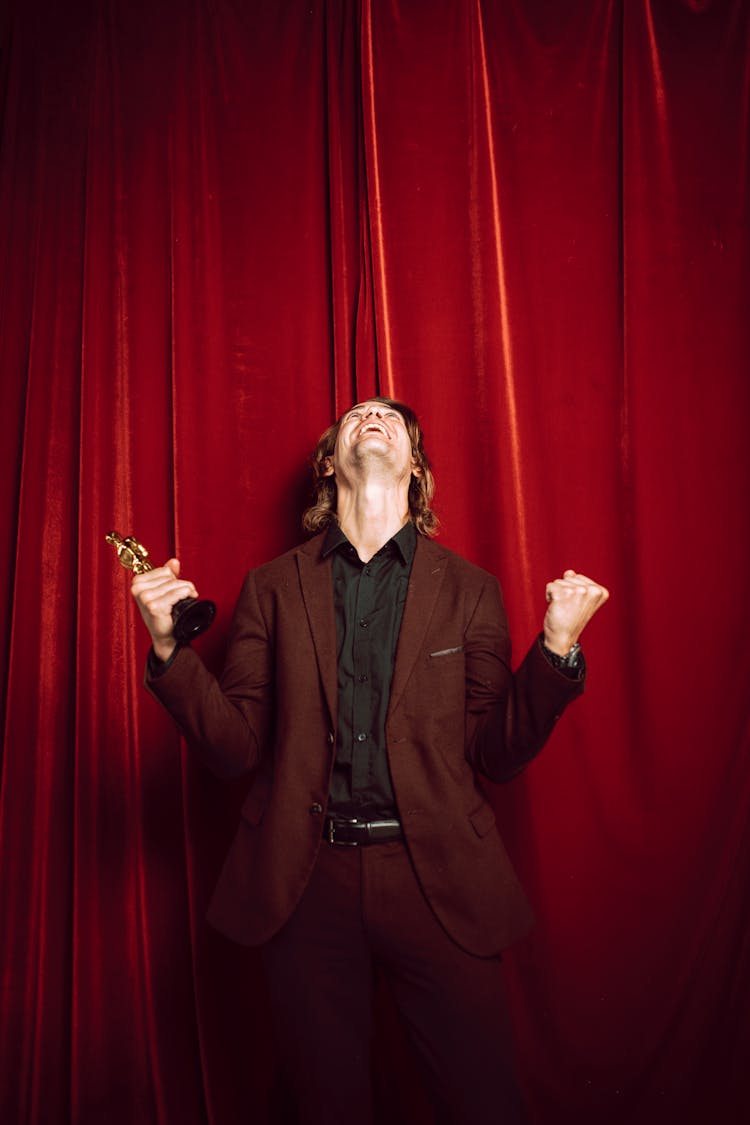 Happy Man In Red Suit Holding A Trophy And Celebrating