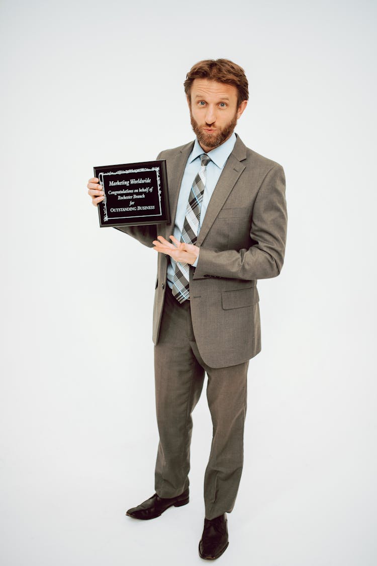 A Man In Gray Suit Holding A Plaque
