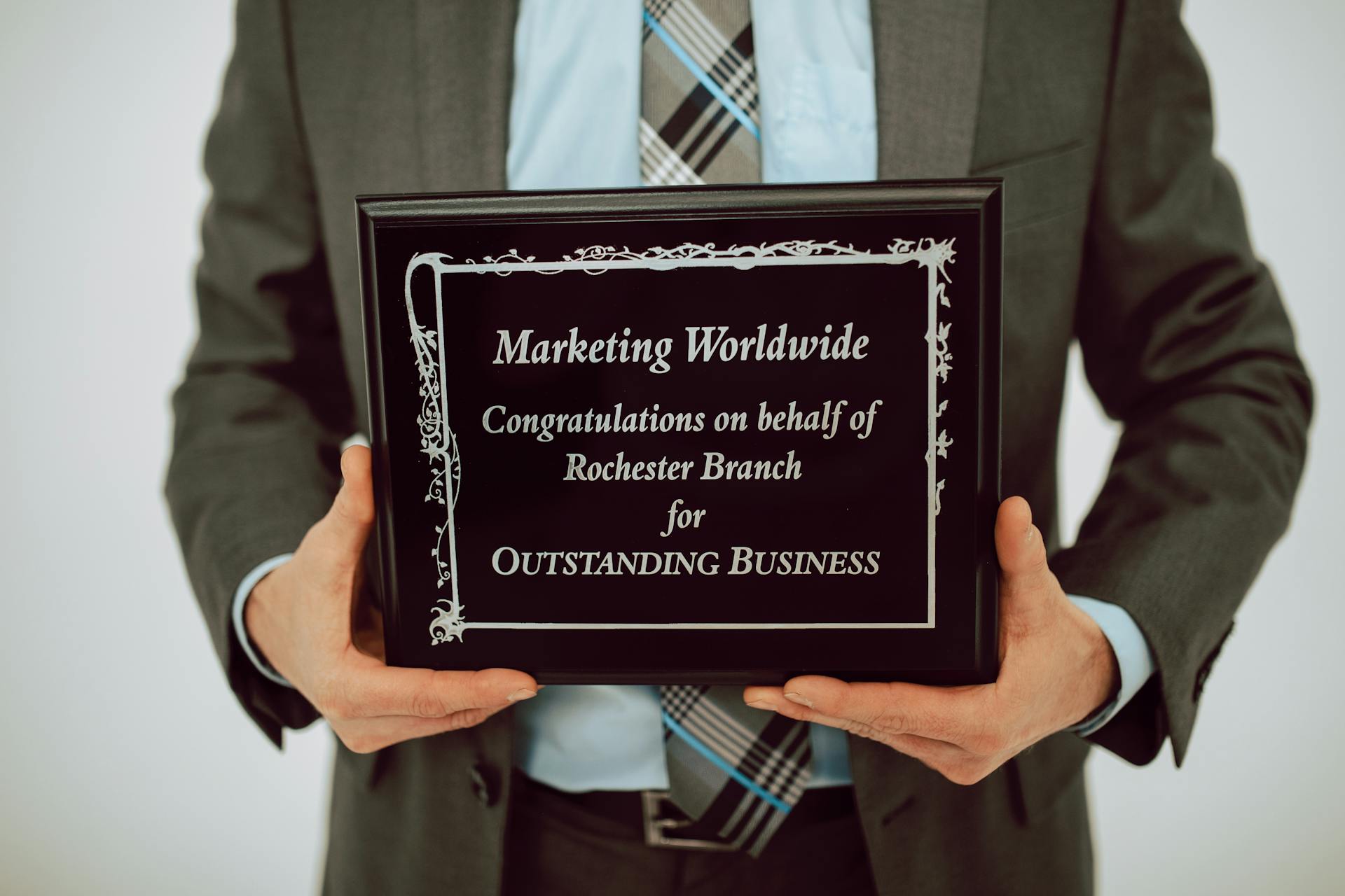 Businessperson holding an award for outstanding business achievement in formal attire.