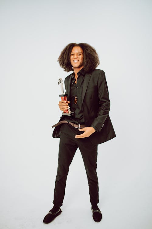 Man in Black Suit Holding a Trophy on White Background