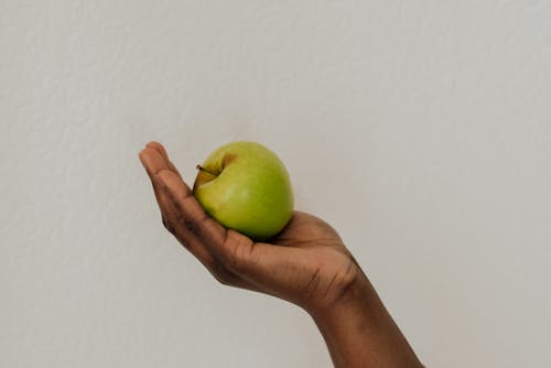 
A Close-Up Shot of a Person Holding a Green Apple