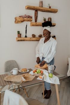 A cheerful woman slices bread for breakfast in a cozy, modern kitchen setting.