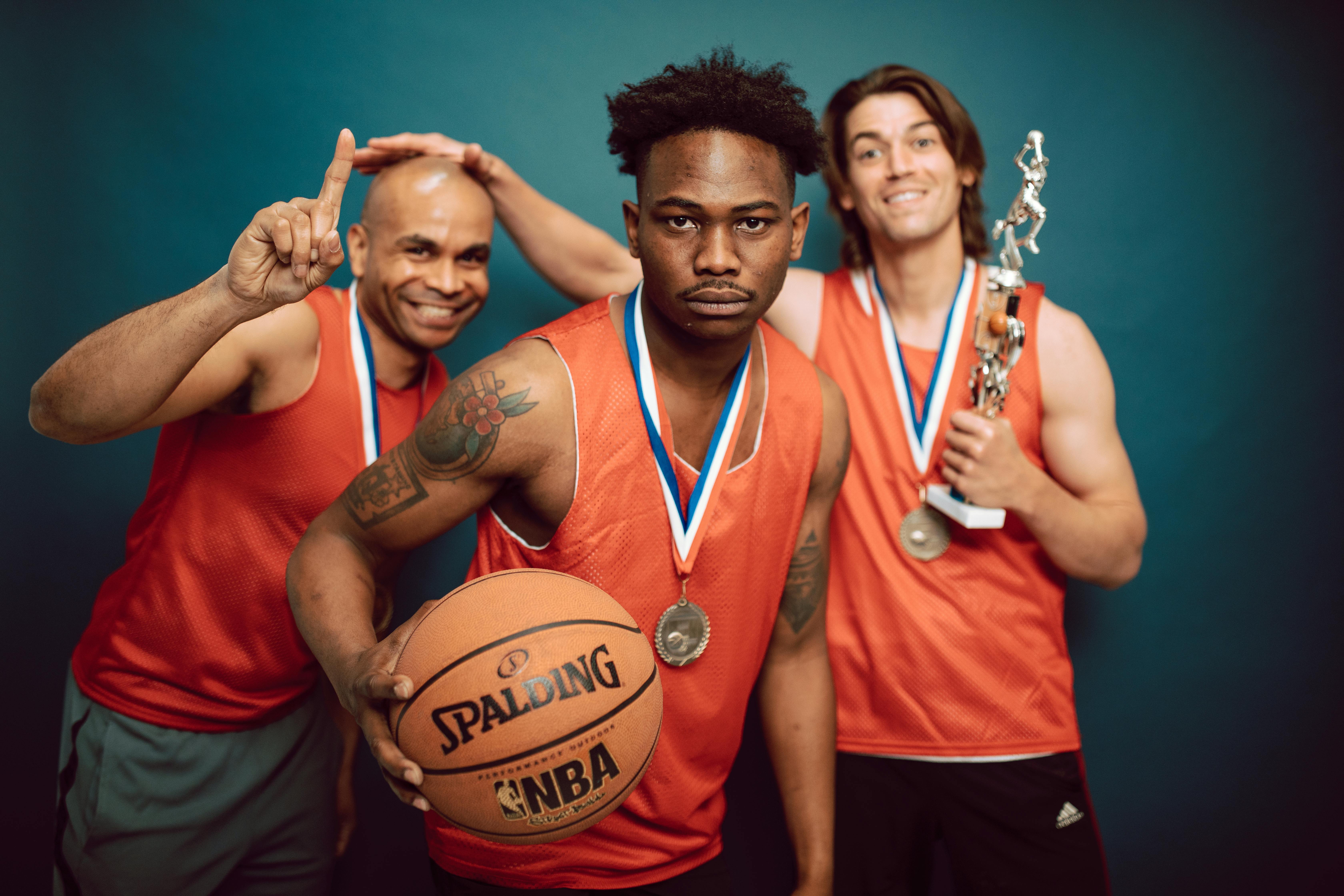 three men in orange jersey shirt holding basketball