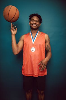 Smiling athlete poses in studio with a basketball and medal, showcasing triumph.
