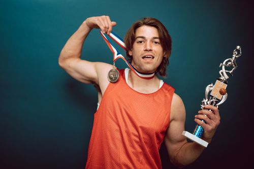 Free Energetic basketball player celebrating victory with a medal and trophy in a studio setting. Stock Photo