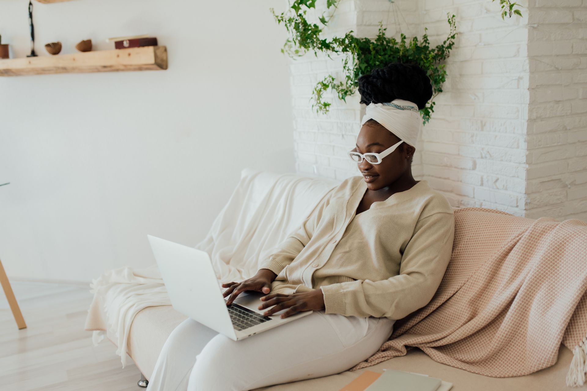A stylish African American woman working remotely on her laptop in a cozy living room setting.