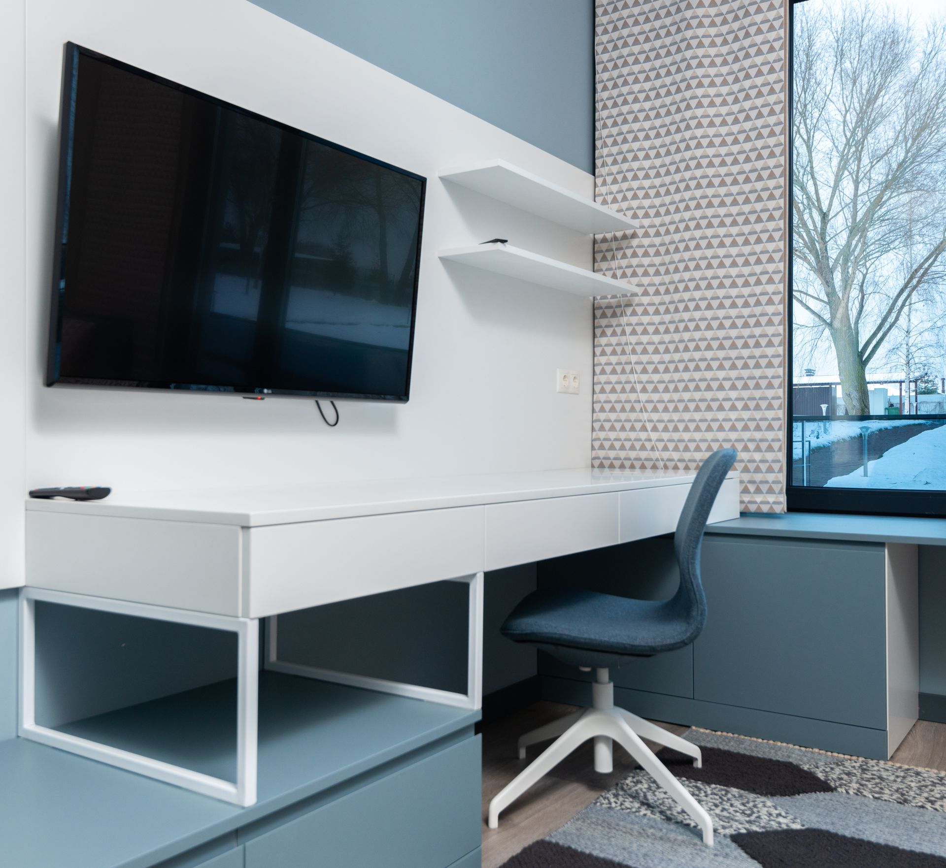 Modern TV hanging on wall over working table with chair