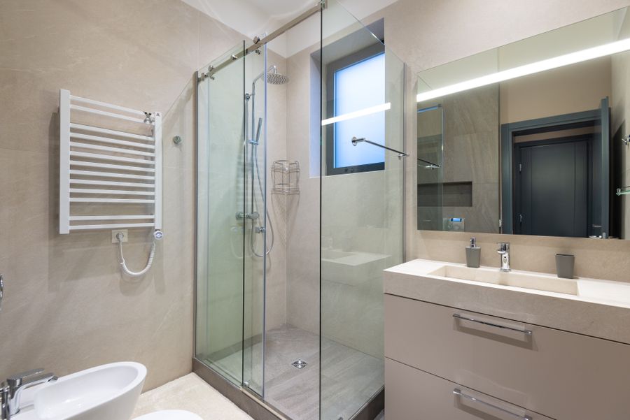 Baño moderno con lavamanos, espejo y ducha de vidrio