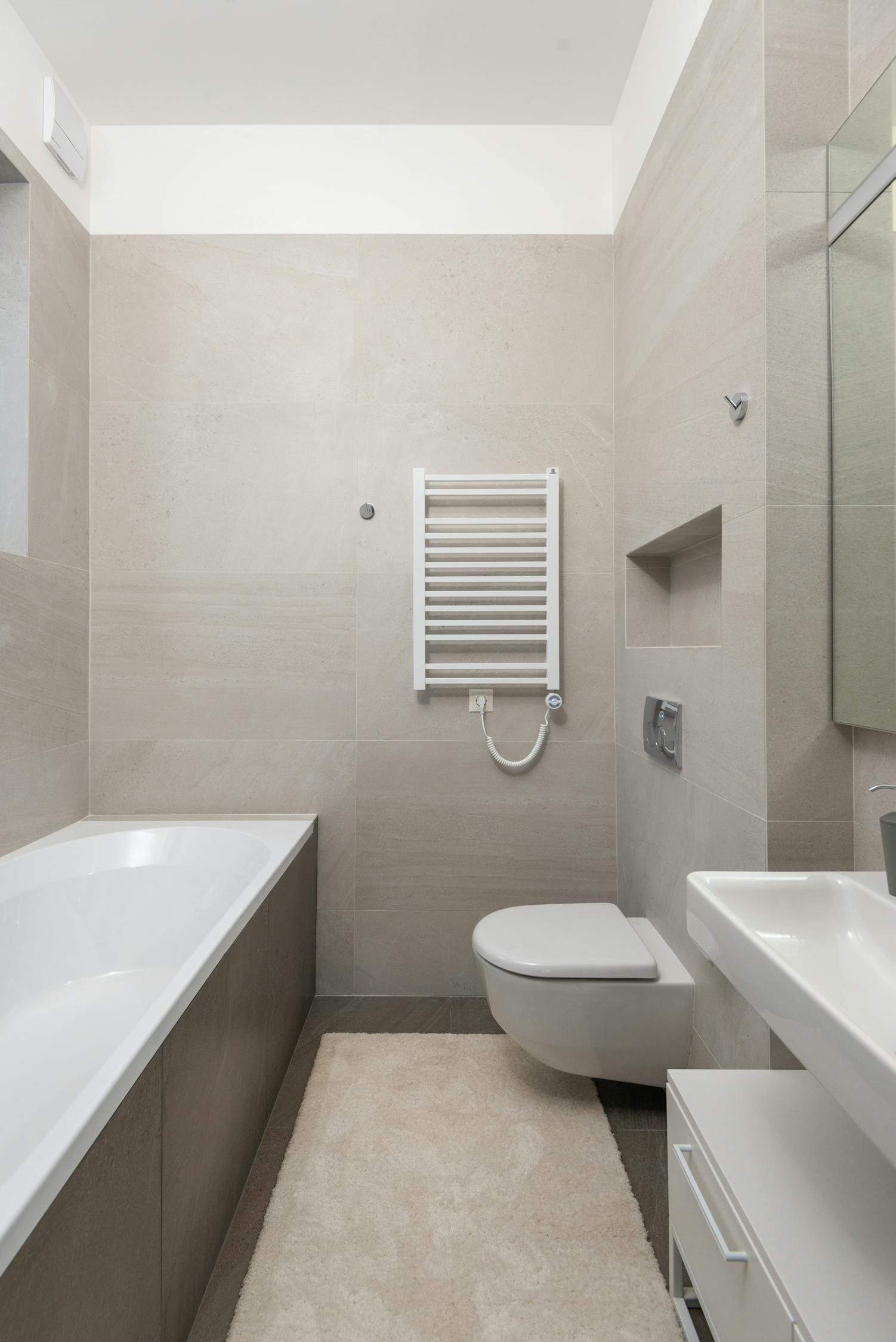 Interior of minimalist styled bathroom with white ceramic bathtub