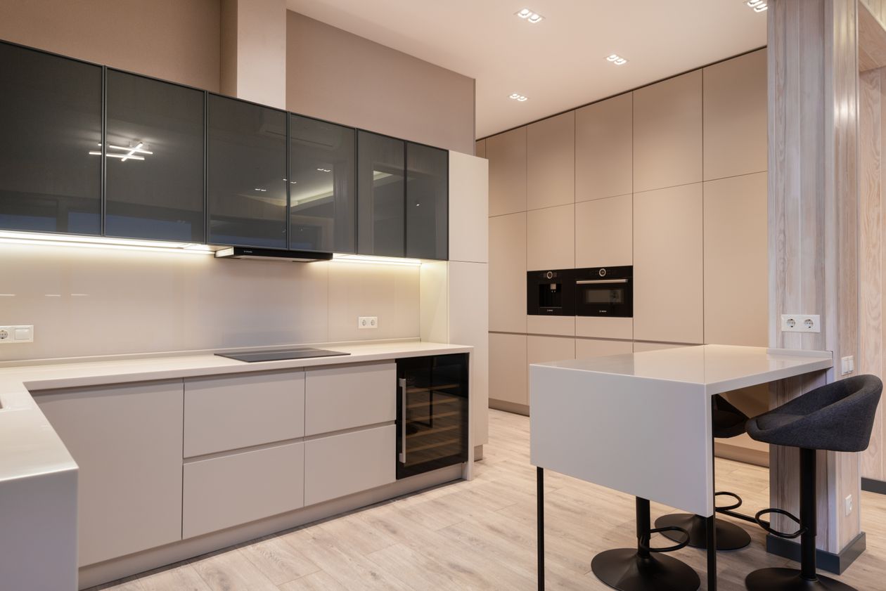 Modern two-tone European kitchen with matte beige lower cabinets and dark glass upper cabinets