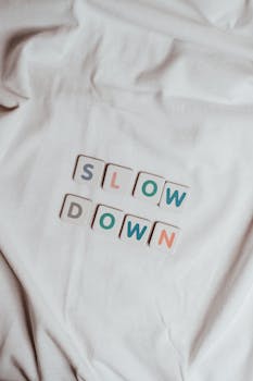 Relaxing conceptual image with 'Slow Down' spelled on fabric, promoting mindfulness.
