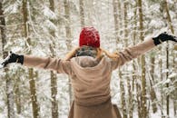一位戴着红帽子的女人在普莱西德湖的森林里享受白雪皑皑的冬日