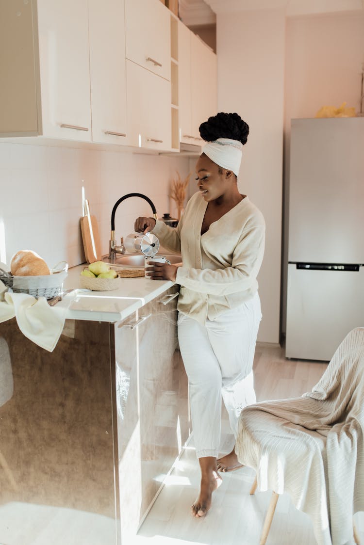 A Happy Woman Pouring A Cup Of Coffee In A Kitchen