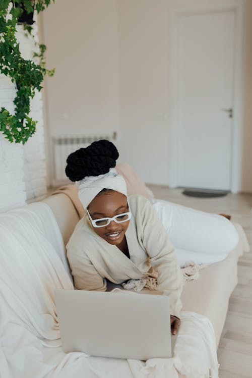 Free A happy Woman Using a Laptop on a Couch Stock Photo