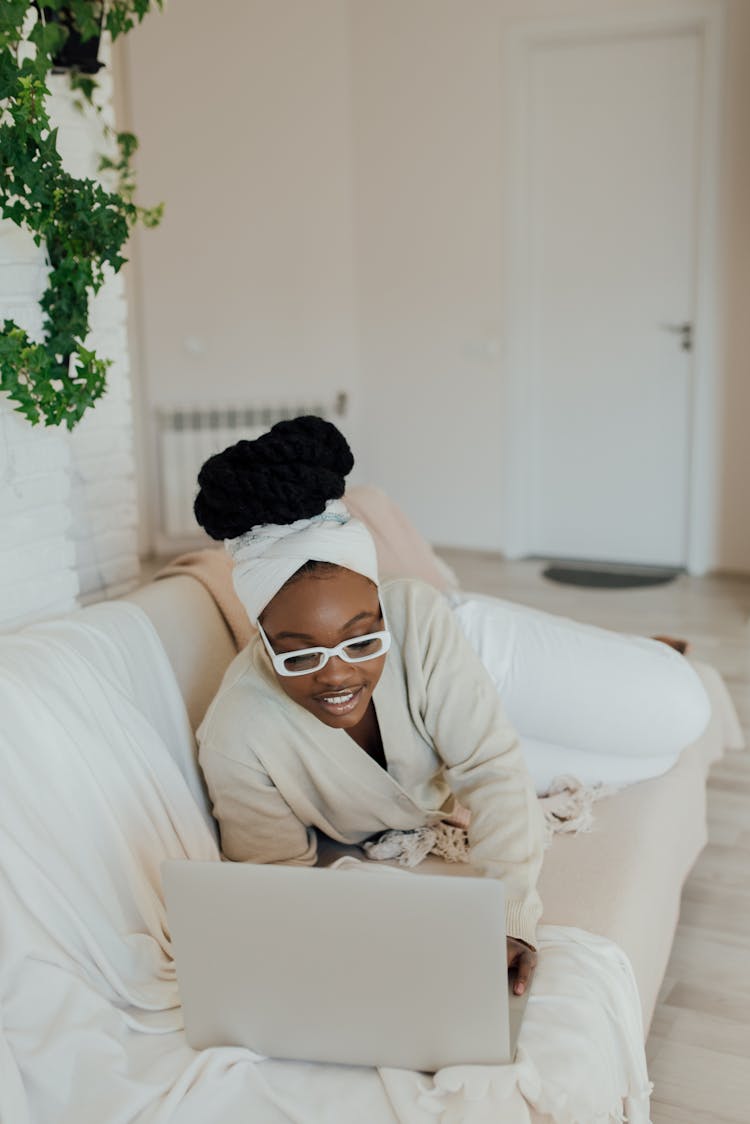 A Happy Woman Using A Laptop On A Couch