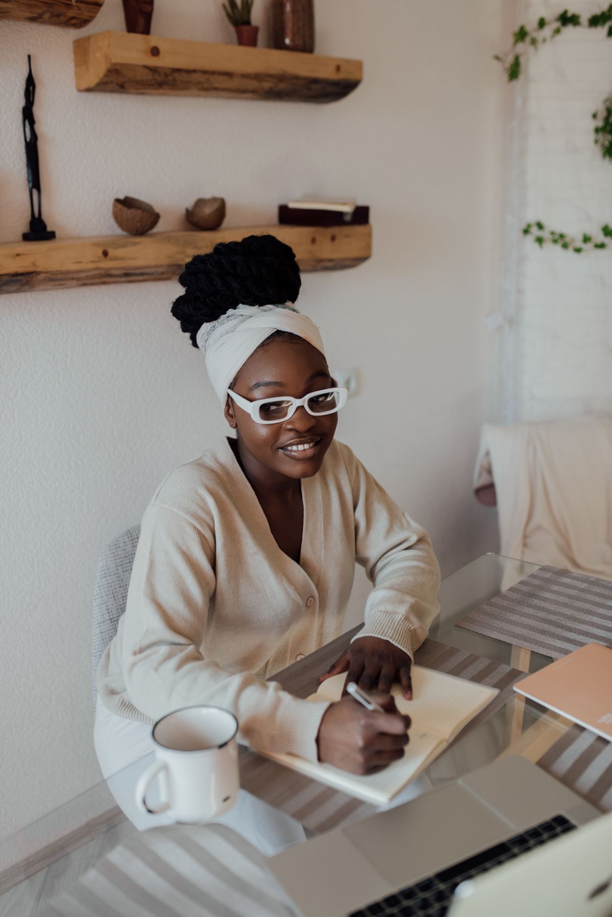 Woman smiling while writing in a notebook at a table