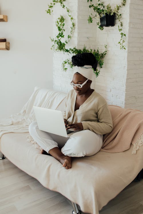 Free A Woman Using a Laptop on a Couch Stock Photo