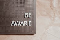 The Phrase Be Aware on a Pin Board