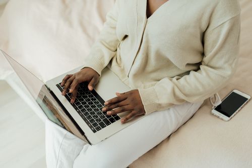 Free Person working remotely on laptop with smartphone nearby. Cozy home setting, lifestyle focus. Stock Photo