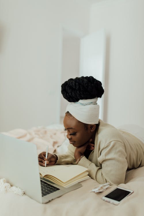 A Woman Writing in Bed on a Notebook
