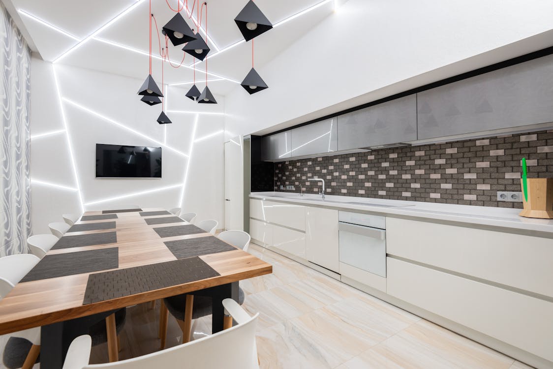 Modern kitchen interior with minimalist white cabinets and wooden table decorated with creative chandelier