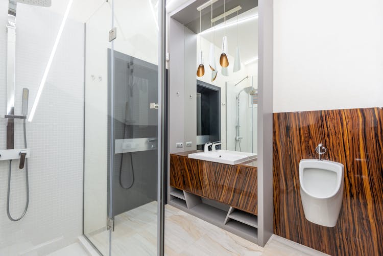 Shower Cabin In Modern Bathroom With Sink And Urinal