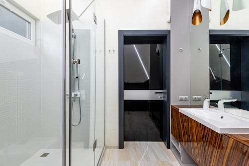 Interior of light contemporary bathroom with shower and glass door in modern apartment