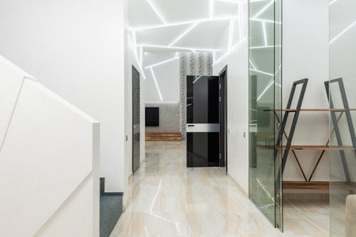 Contemporary corridor interior with doors and ornamental walls illuminated by lamps above laminate in house