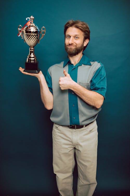 A Man with a Trophy Giving a Thumbs up