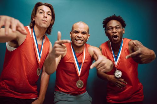 Free Three athletes in red jerseys celebrate with medals, showcasing team spirit. Stock Photo