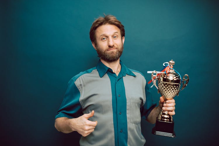 A Man Posing While Holding A Trophy