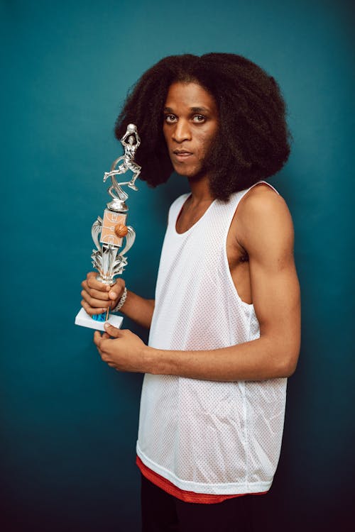 
A Man in a Perforated Tank Top Holding a Trophy