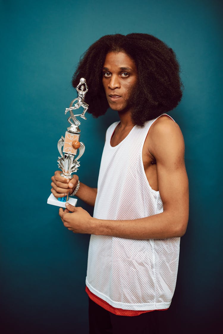 
A Man In A Perforated Tank Top Holding A Trophy