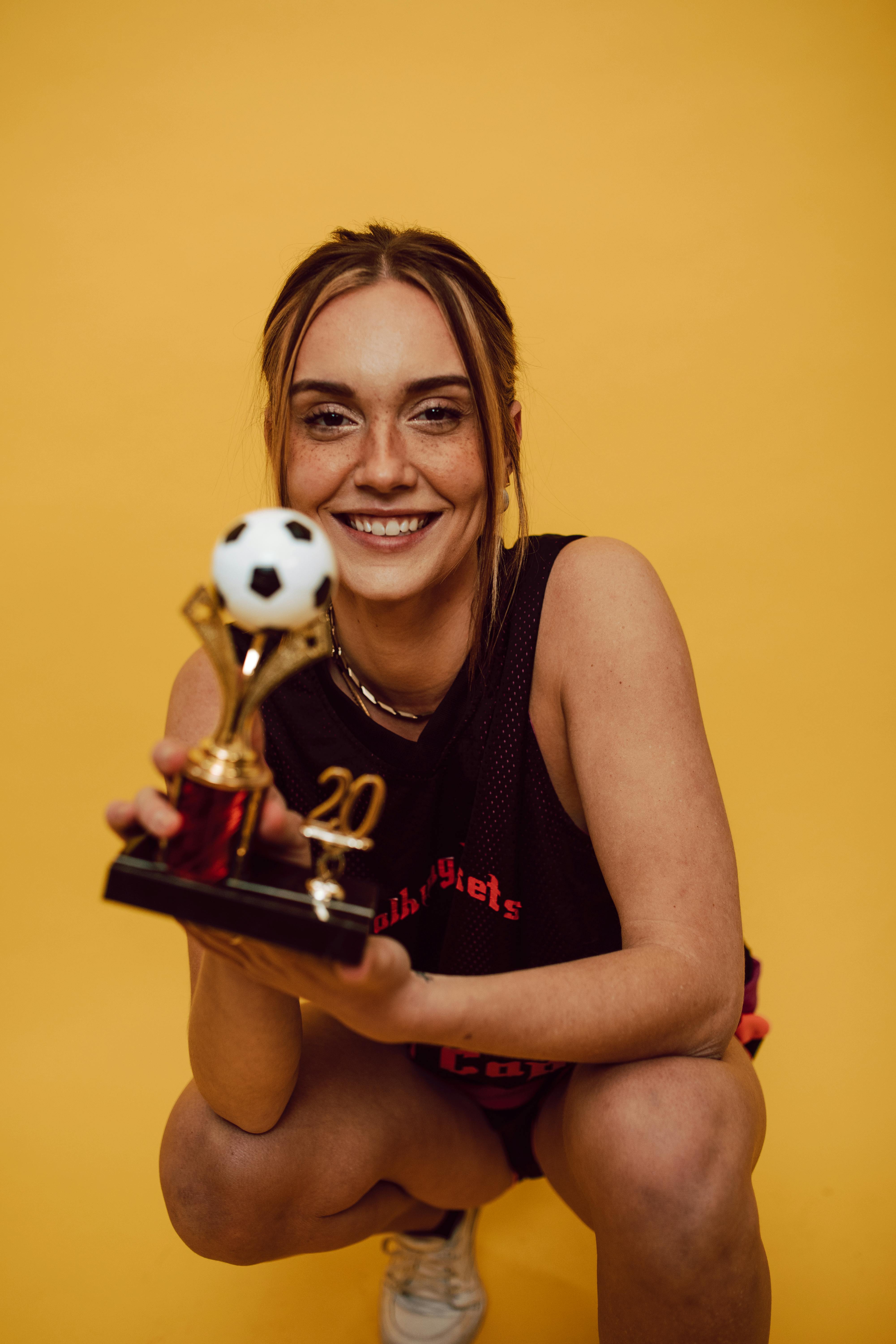 a smiling woman holding a trophy