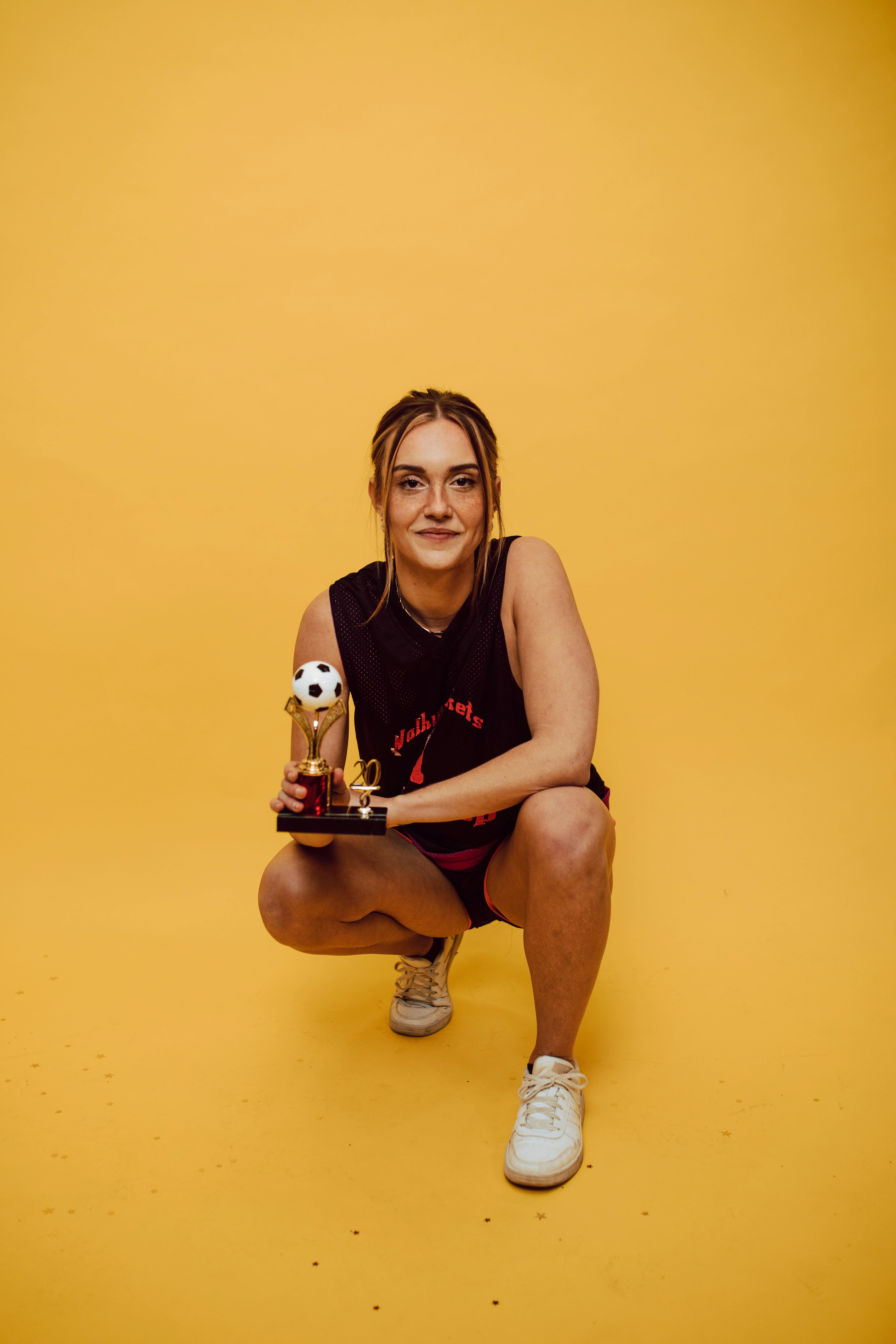 a woman crouching while holding a trophy