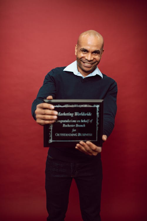 Free A Smiling Man Holding a Certificate of Appreciation Stock Photo