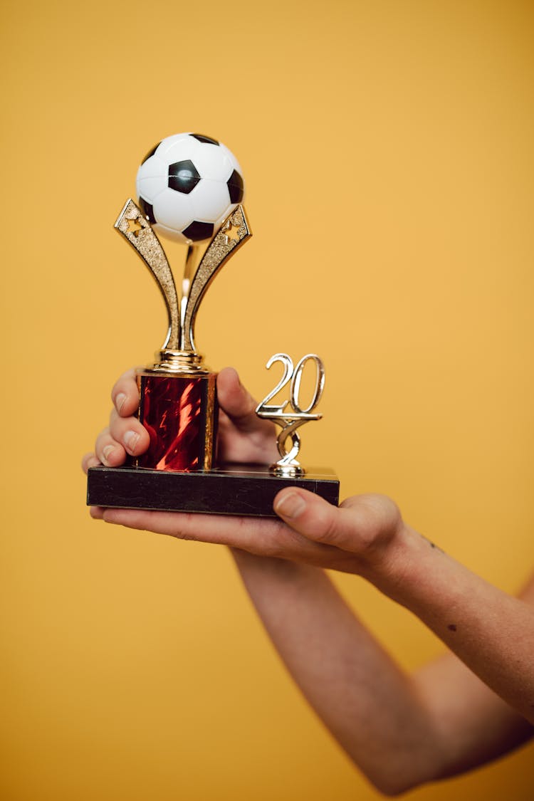 A Person Holding A Soccer Trophy