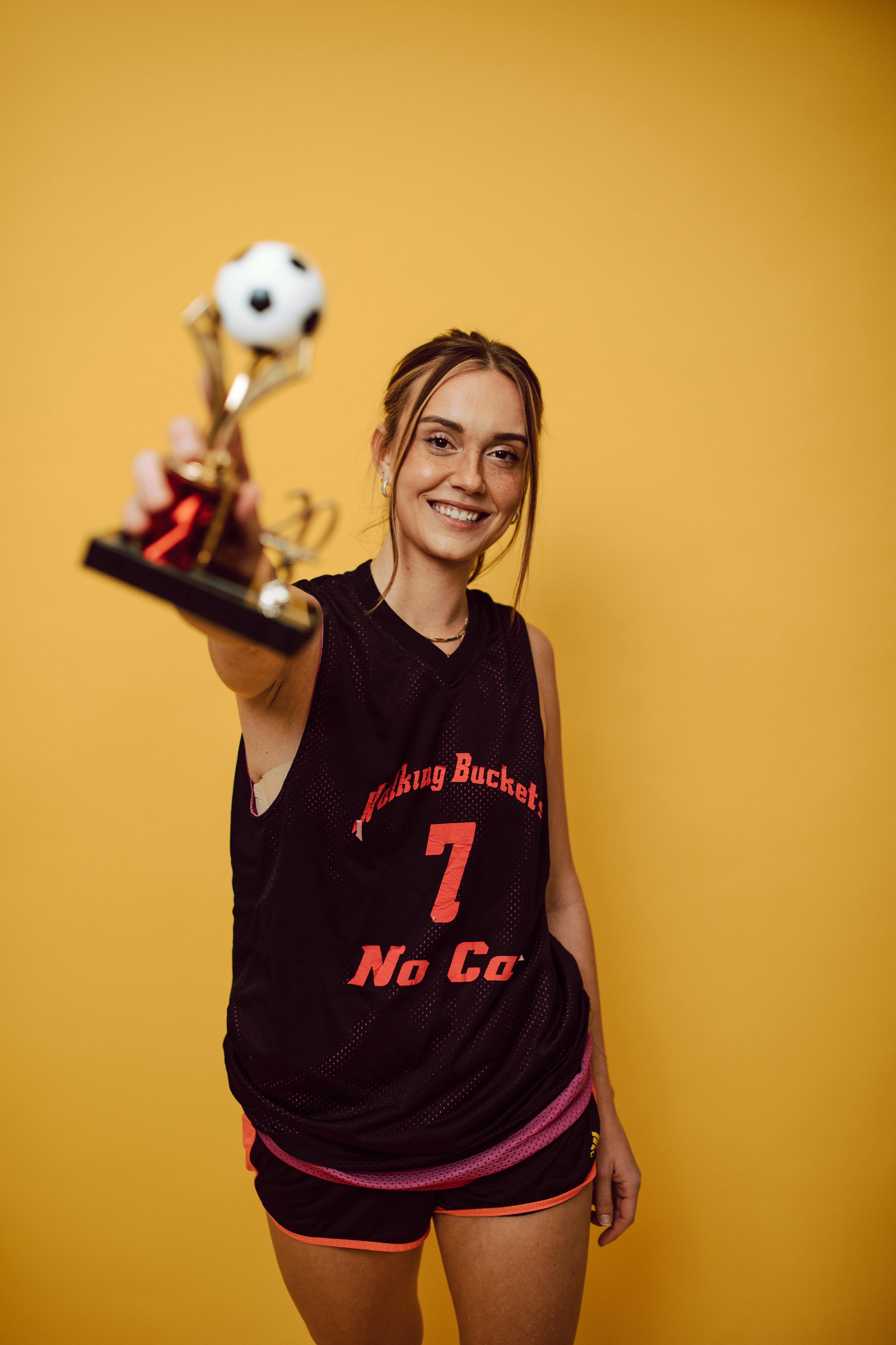 a female soccer posing with a trophy