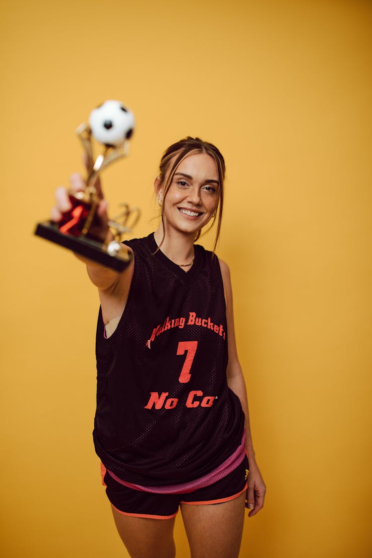 A Female Soccer Posing With A Trophy